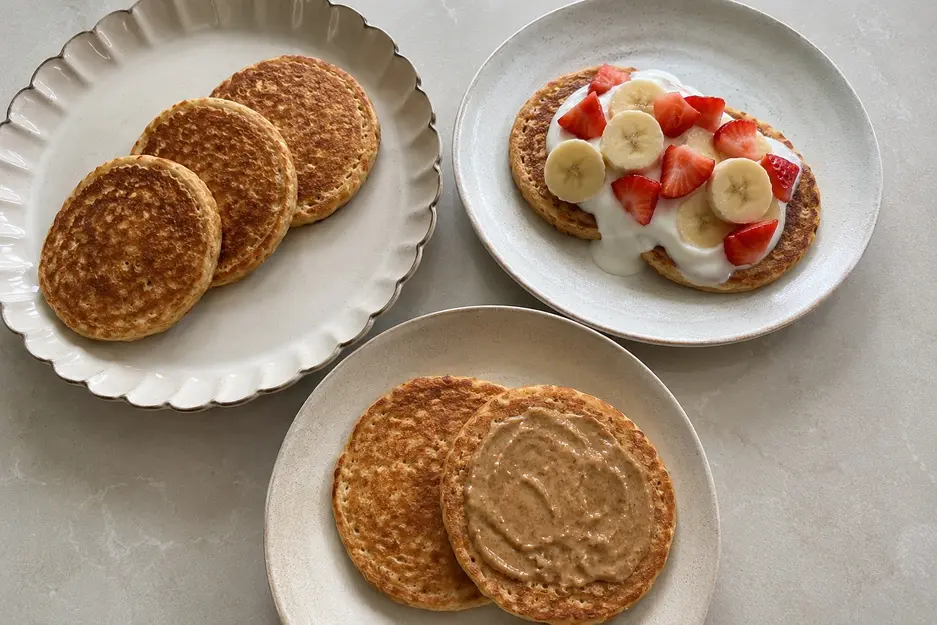 Banana oat pancakes for baby served three ways: plain, topped with yogurt and fresh fruit, and spread with a thin layer of nut or seed butter.